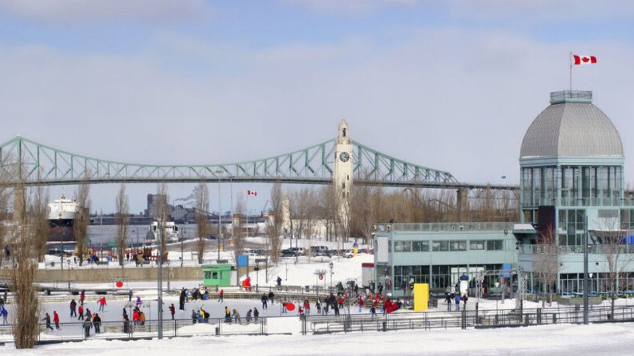 Old Port of Montreal ice skating rink with Jacques Cartier Bridge in the background during the winter.