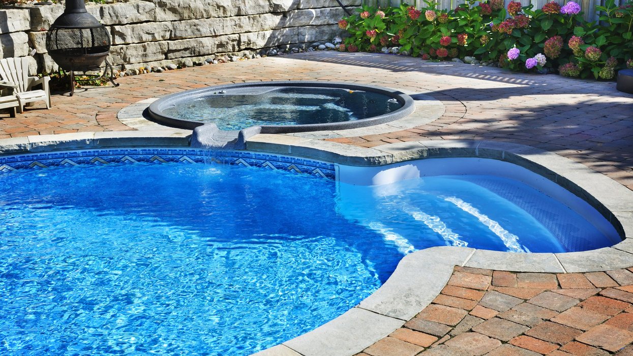 Outdoor inground residential swimming pool in backyard with hot tub