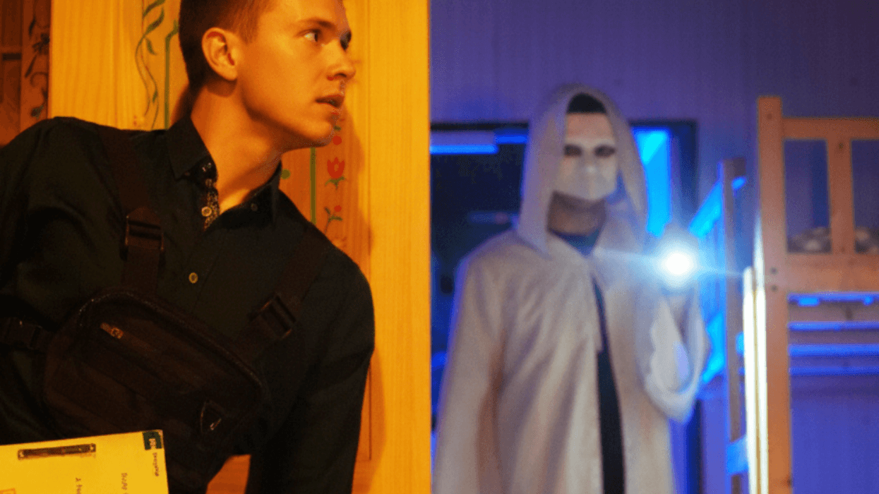 Participant hiding from a masked figure during a spy-themed escape room.