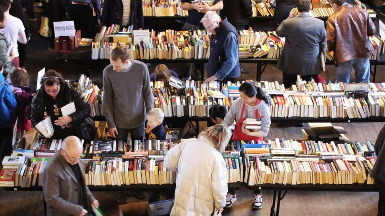 People browse books piled atop multiple tables at a former Friends of the Library book sale.