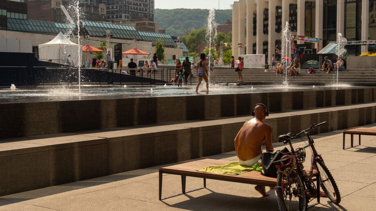 People cooling off in the water basins of Esplanade of Place des Arts during a hot day.