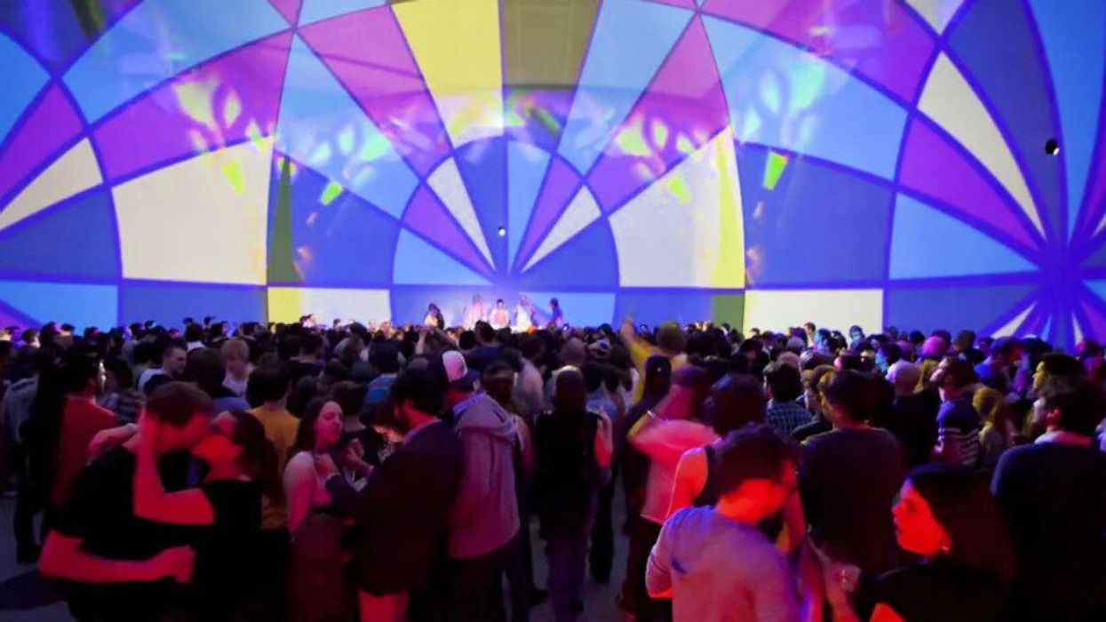 People dance (and kiss) under the illuminated SAT dome.