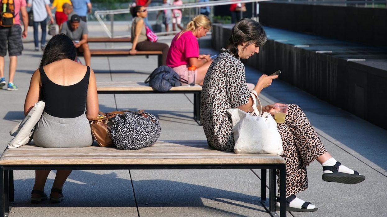 People gaze at the phones on park benches in Montreal.