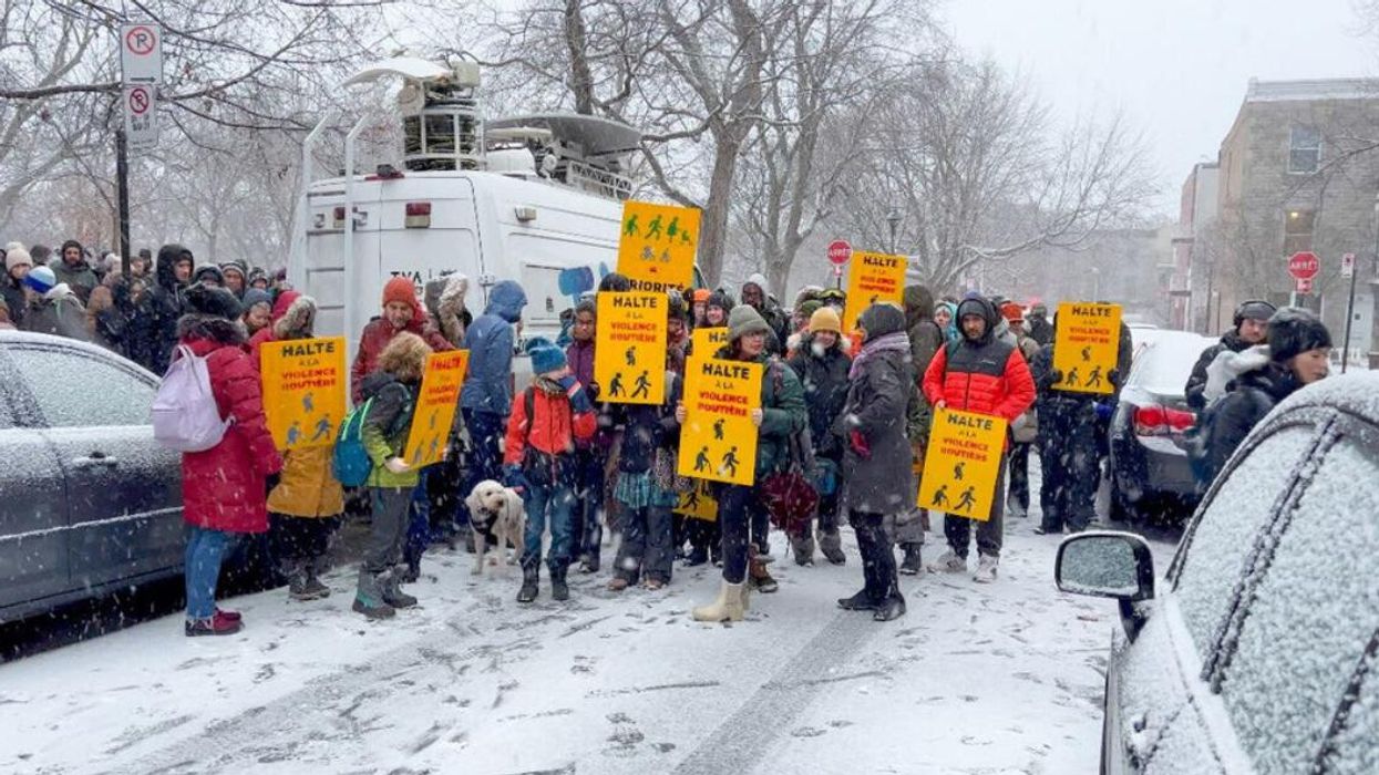 People hold signs standing on a snowy street.