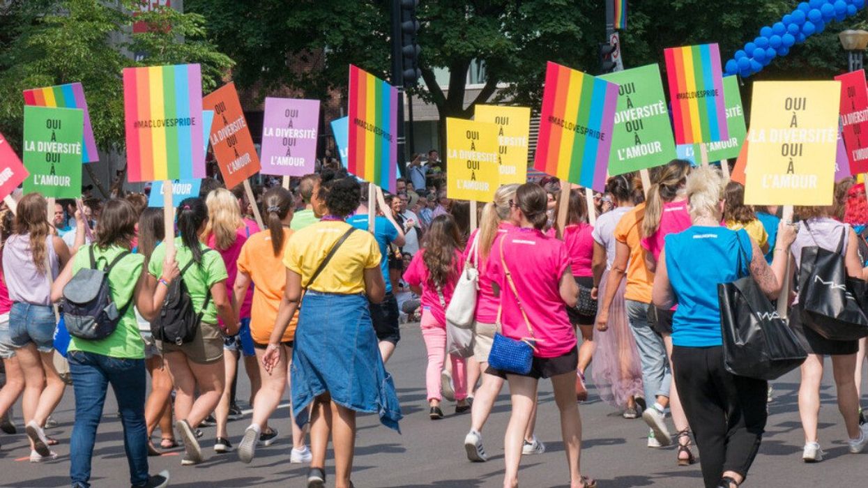 People march holding rainbow signs in Montreal.