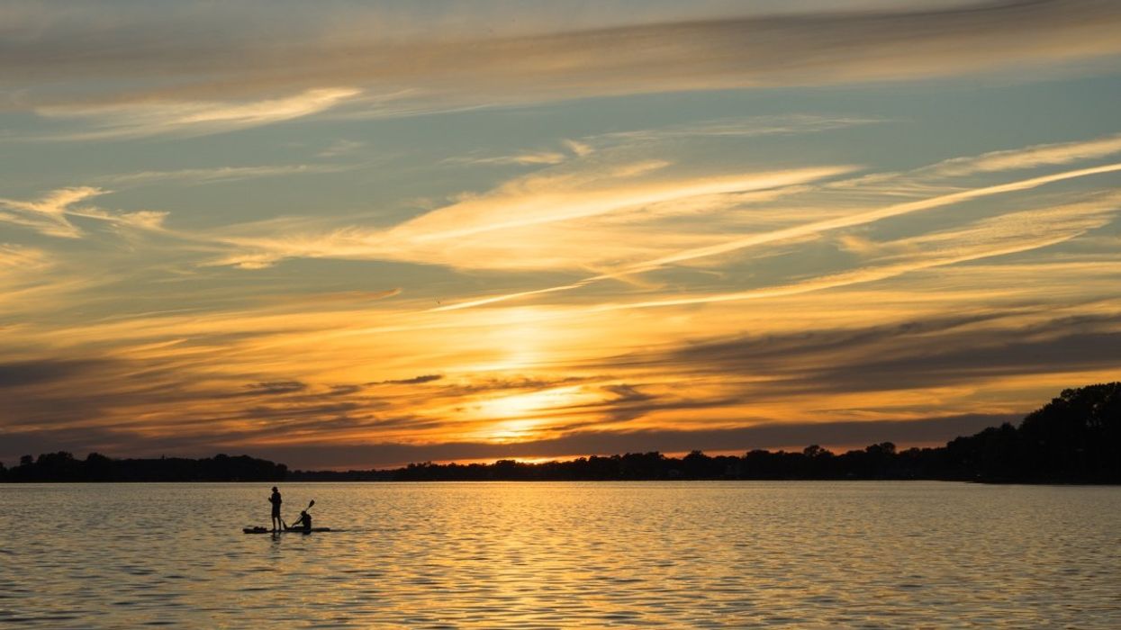 People paddleboarding by the Lachine canal while the sun sets in the background.