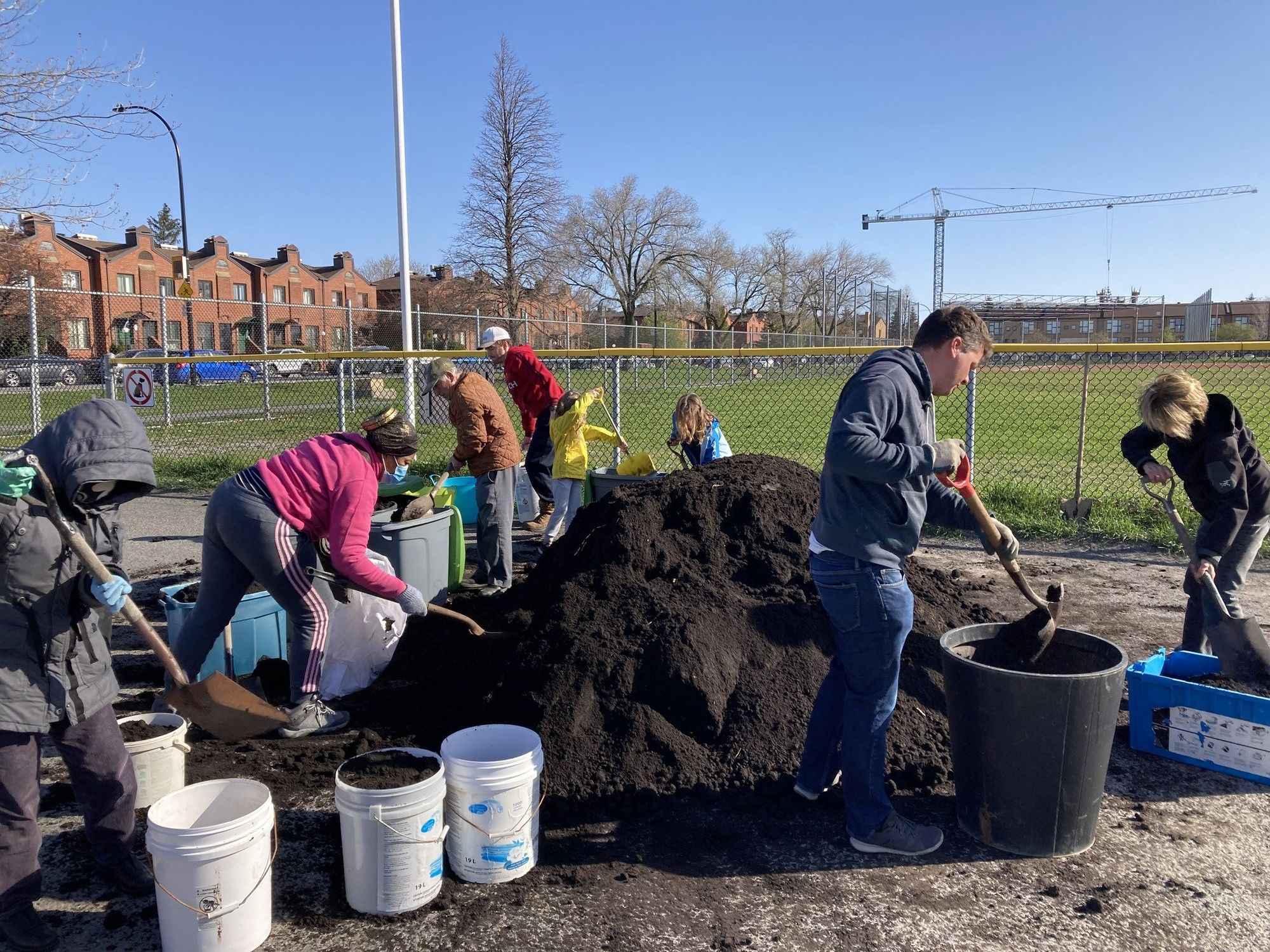 People shovel compost into bins in Anjou.