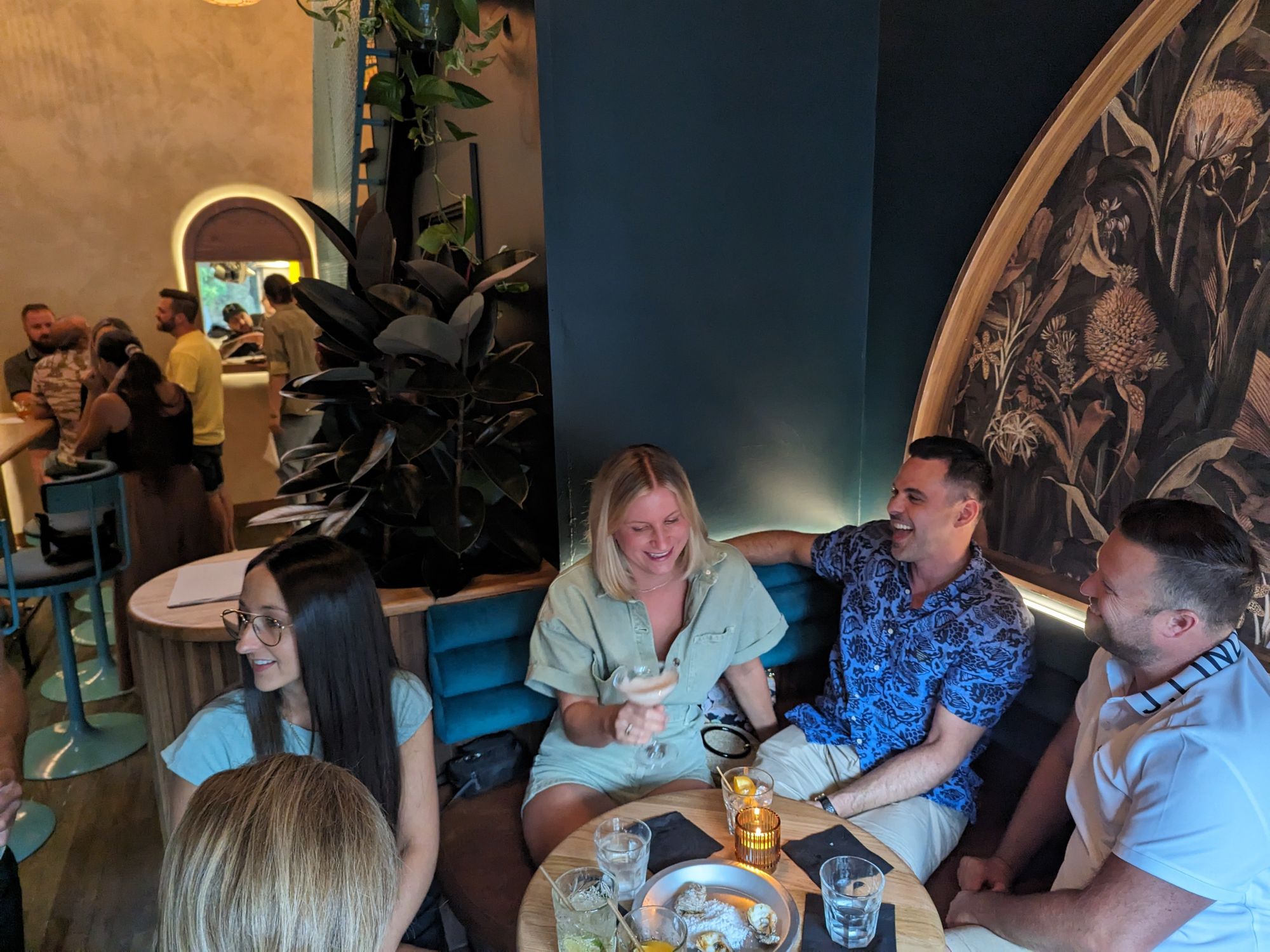 People sit in a booth with cocktails at Moqueur.