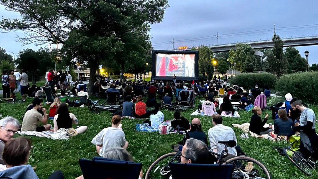 People sit on grass near the Lachine Canal to watch an open-air film at a Montreal festival.