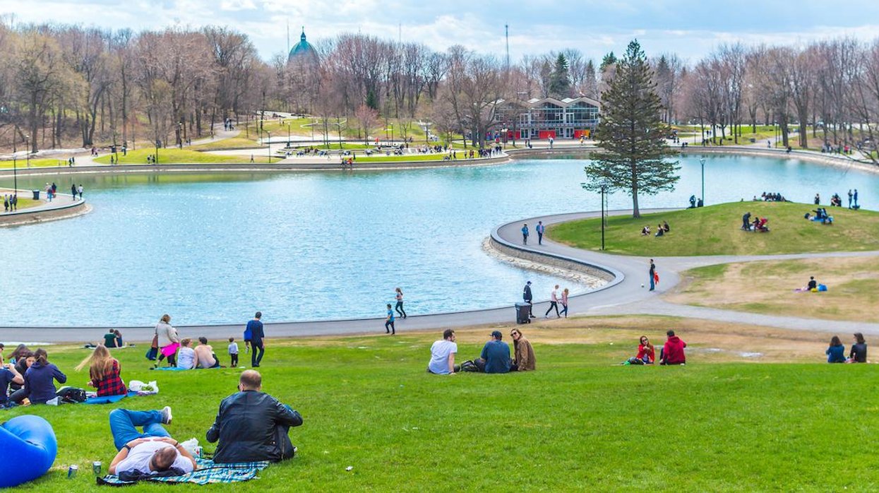 People sitting around Beaver Lake in Montreal's Mount Royal Park on a spring day.