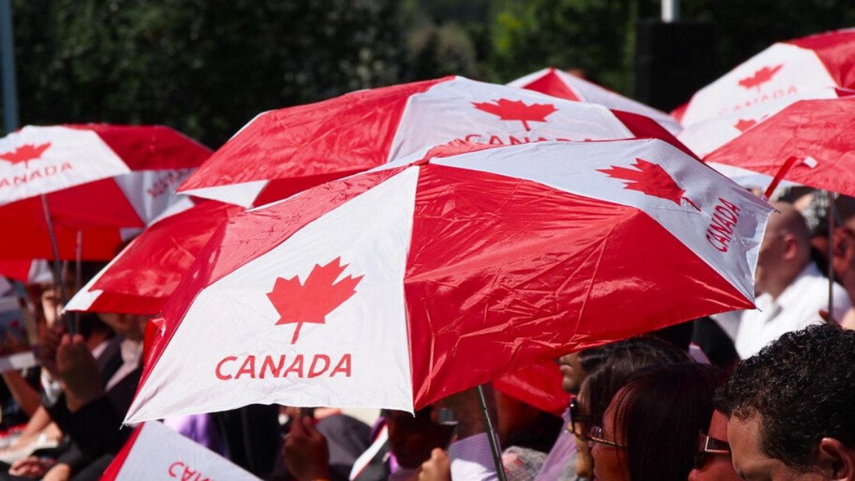 People using Canada Day umbrellas to block the sun.