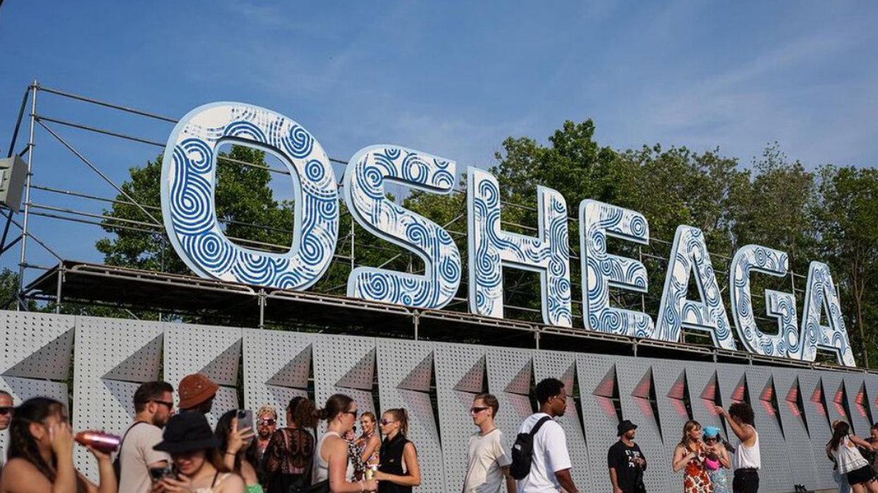 People walk in front of large letters that read 'Osheaga.'