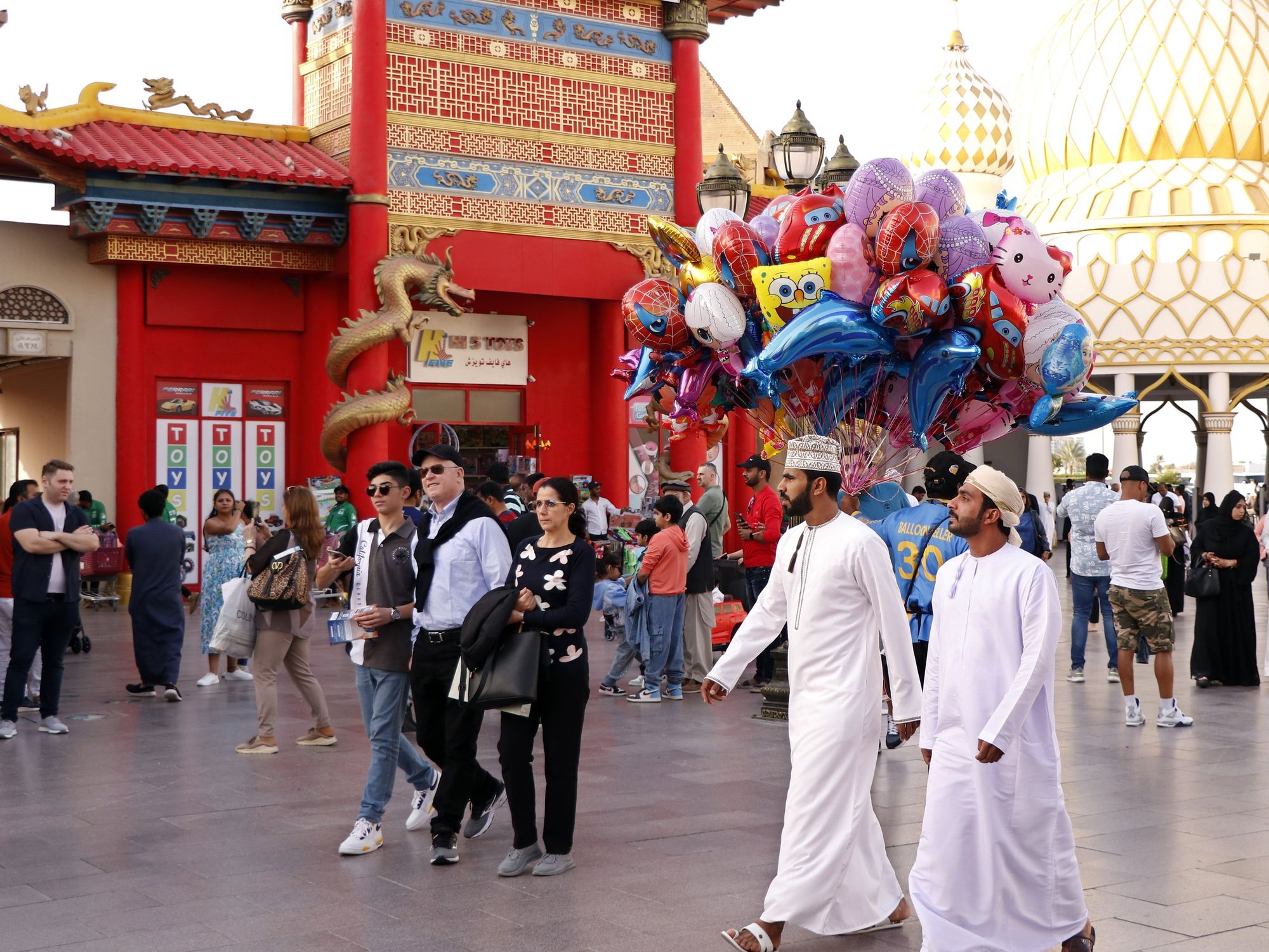 People walk past buildings borrowing from Chinese and Russian architecture in Dubai's Global Village tourist attraction.