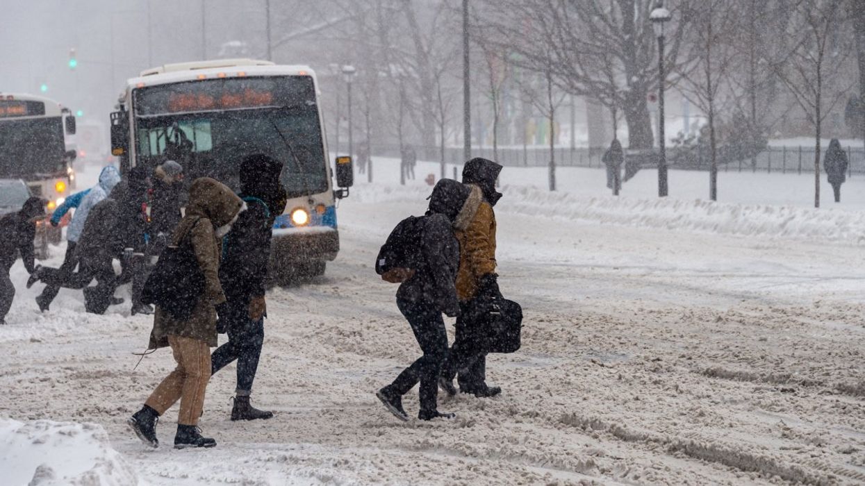 People walking across a street in Montreal during as snow storm.