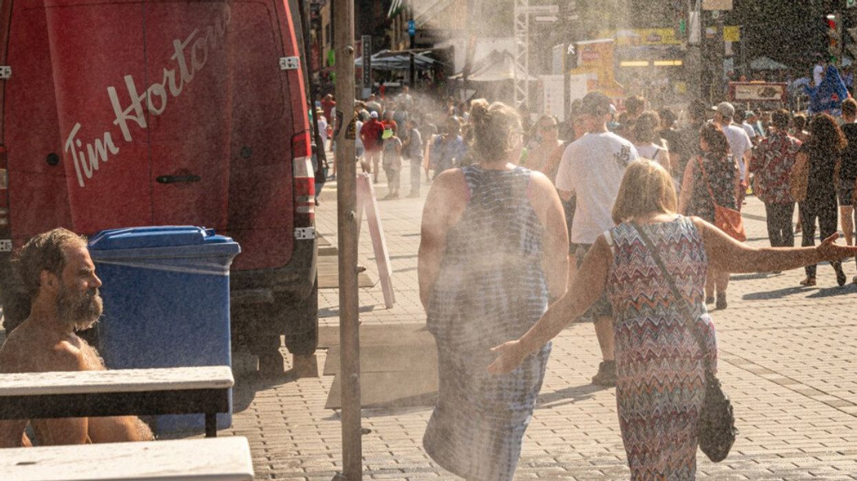 People walking under misting system to cool off during heatwave in Montreal.