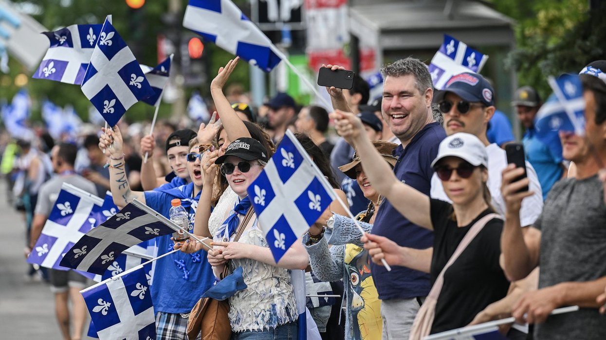 People wave Quebec flags and cheer at a parade.