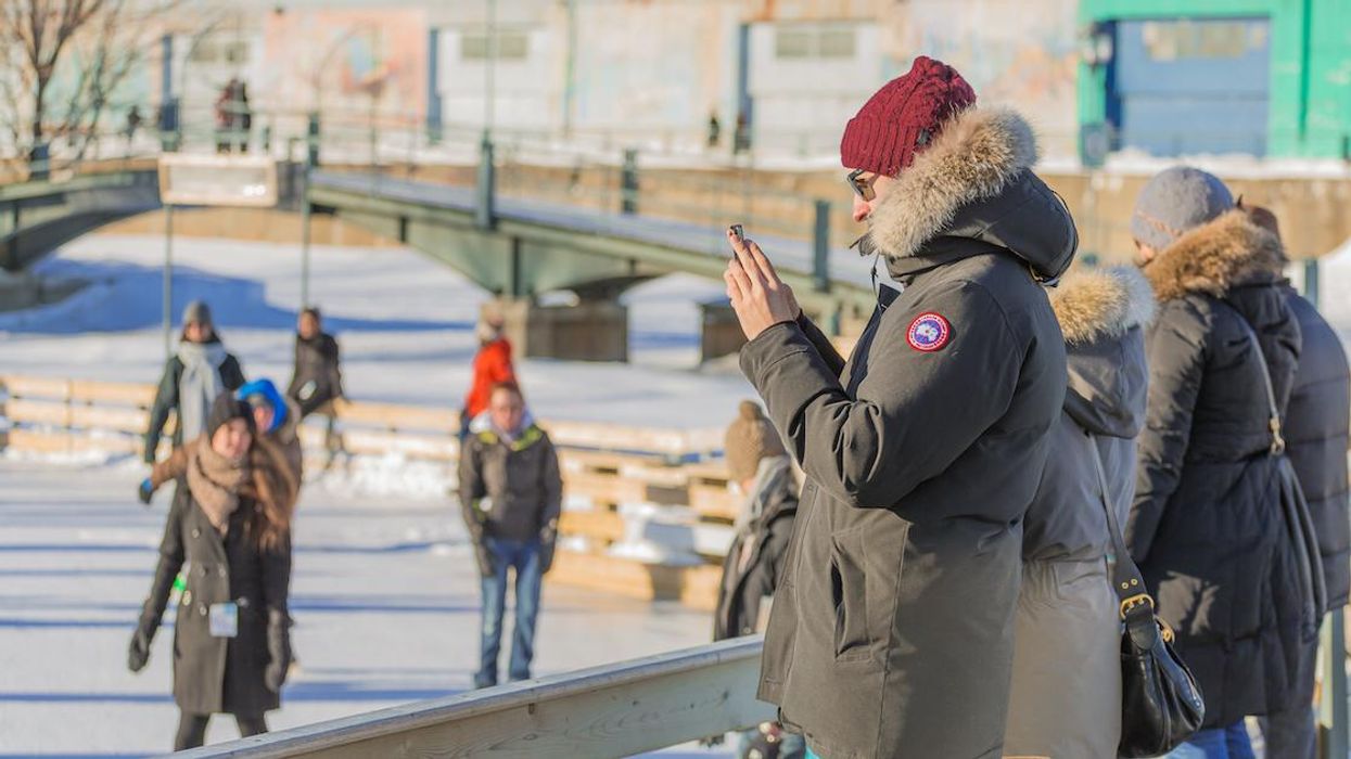 Person on their phone at an outdoor Montreal ice rink.
