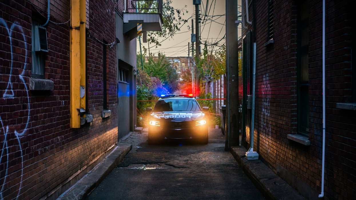 Photo of a police car in a dark alley in Montreal, Canada with flashing red and blue lights