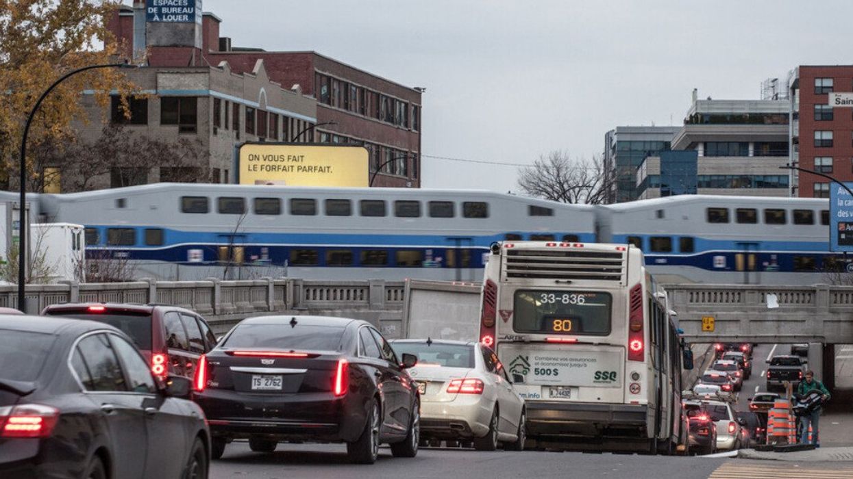 Picture of a train of Exo Montreal crossing the St Laurent Boulevard, jammed and packed with cars and buses during rush hour in Montreal.