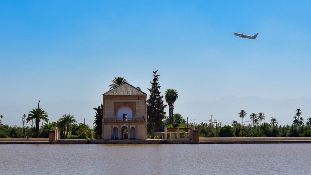 Plane flying over the Menara Gardens in Marrakech, Morocco.