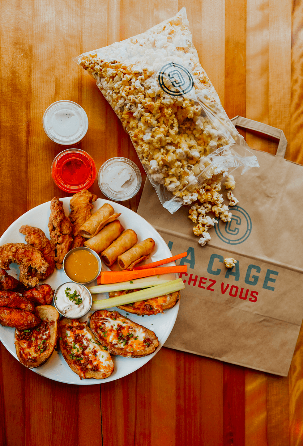 Popcorn, potato skins, wings, fried chicken, arranged on takeout paper bag from La Cage.