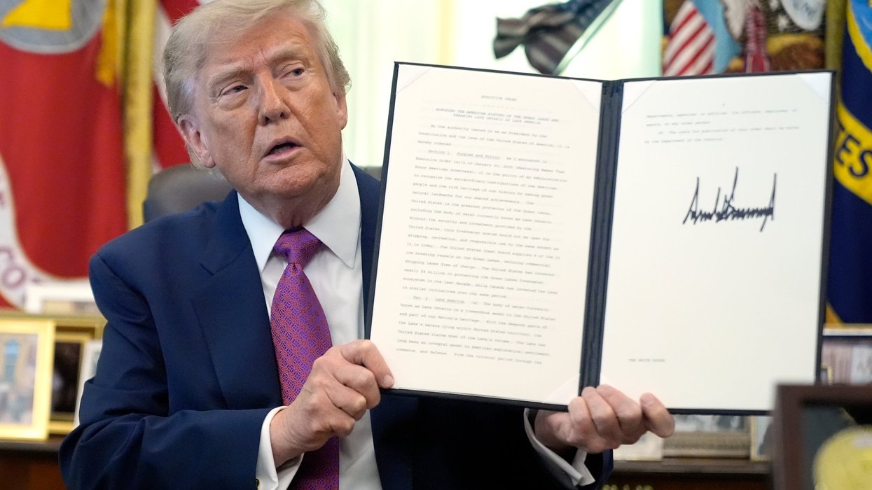 President Donald Trump holds up a signed executive order in the Oval Office of the White House.