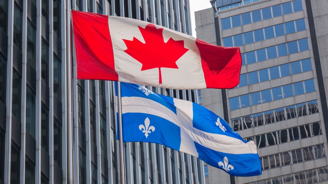 Quebec and Canada flags fluttering in the wind together in downtown Montreal.