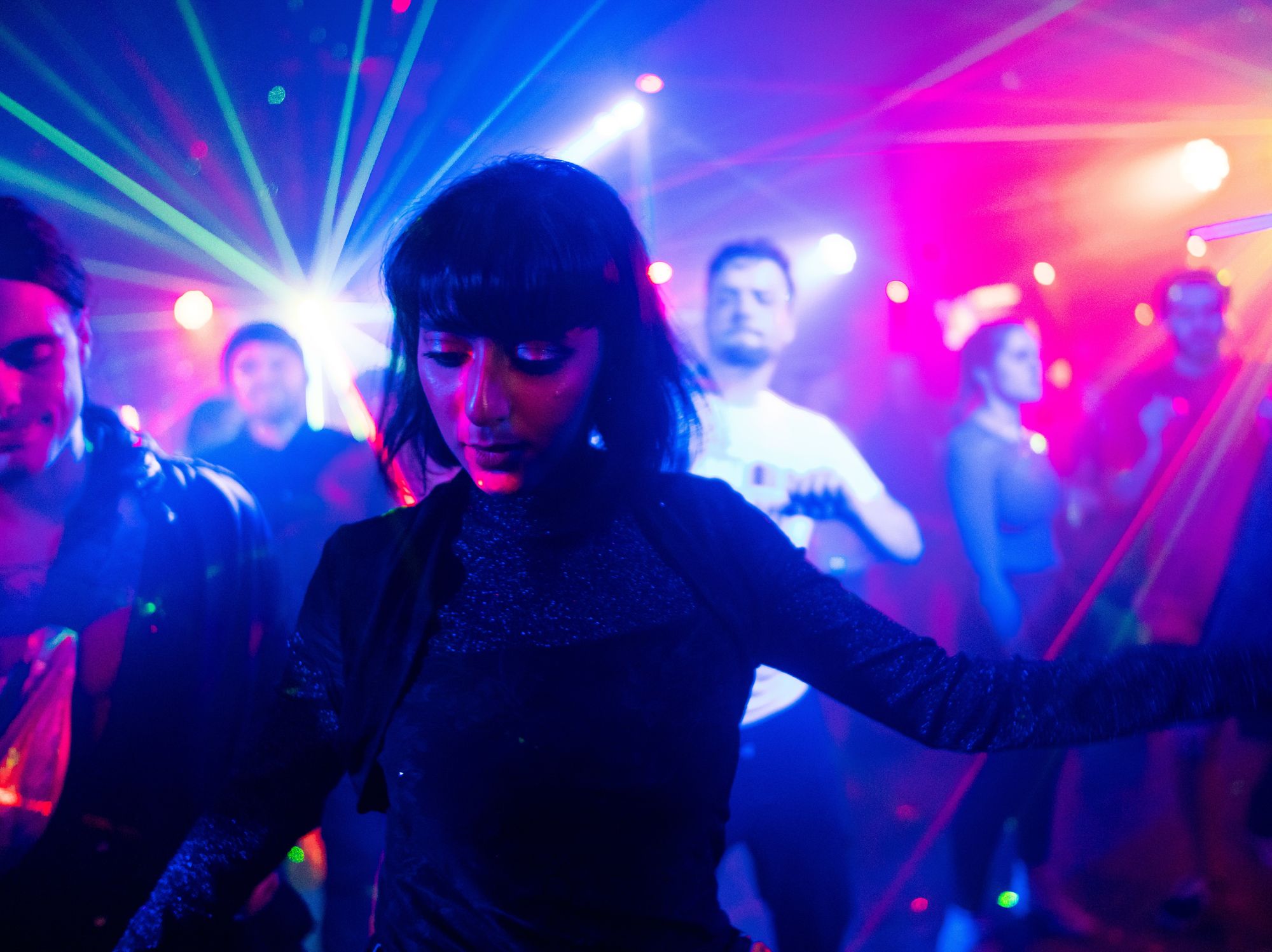 Rainbow-coloured lights illuminate the face of someone on the dancefloor.