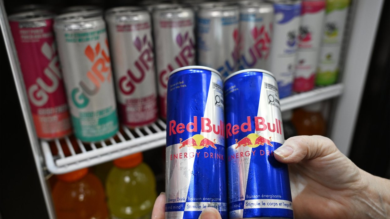 Red Bull energy drink cans being taken out of a drink fridge.