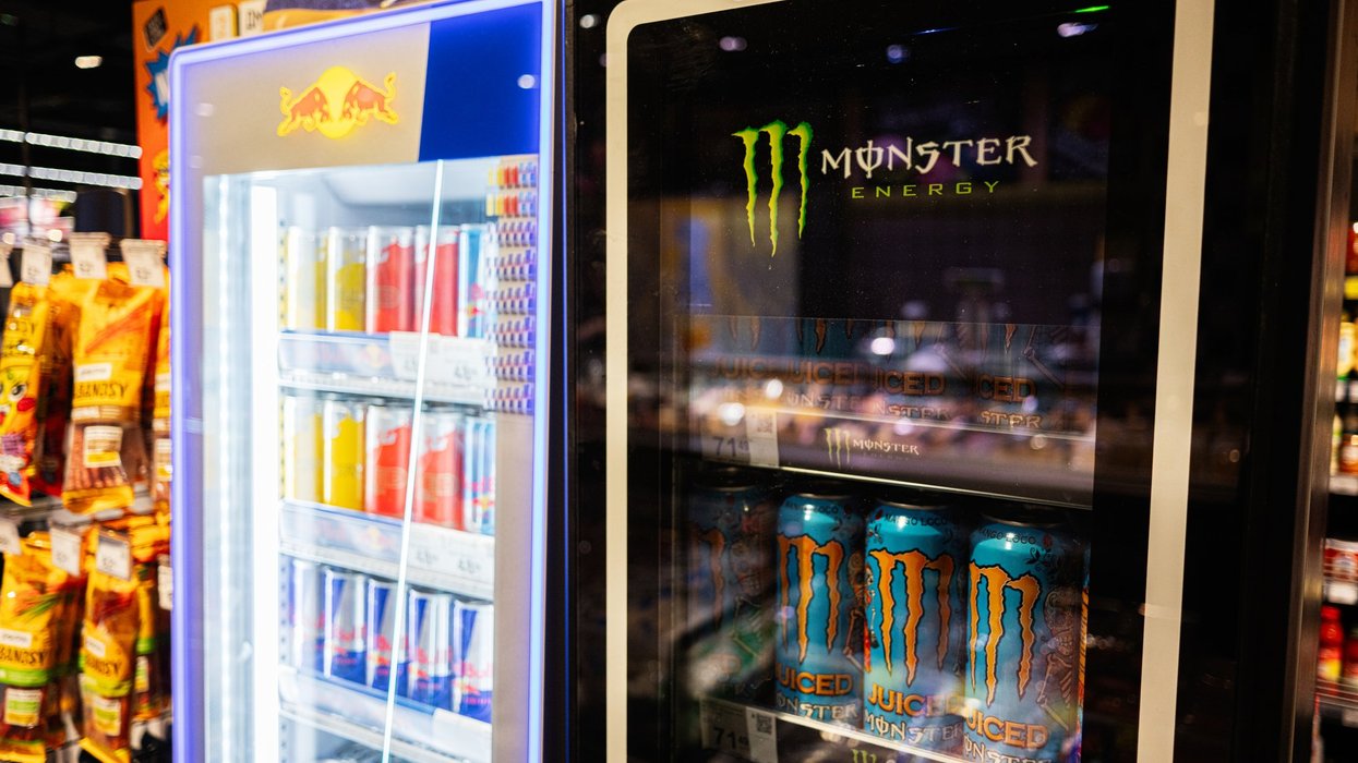 Refrigerated display of Red Bull and Monster Energy drinks at a convenience store.