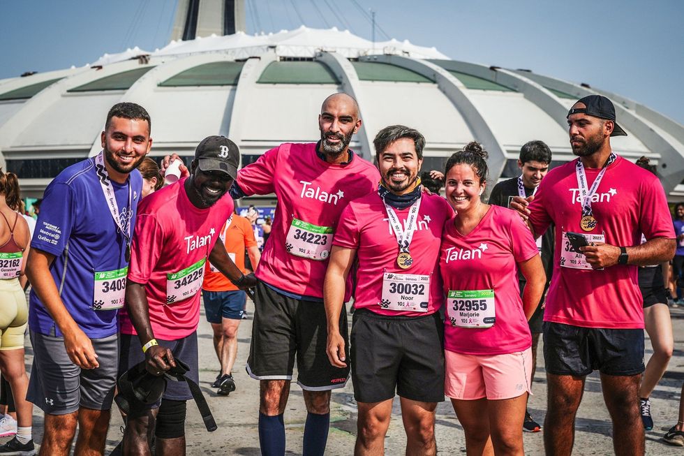 Runners wearing Talan shirts in front of the Olympic Stadium.