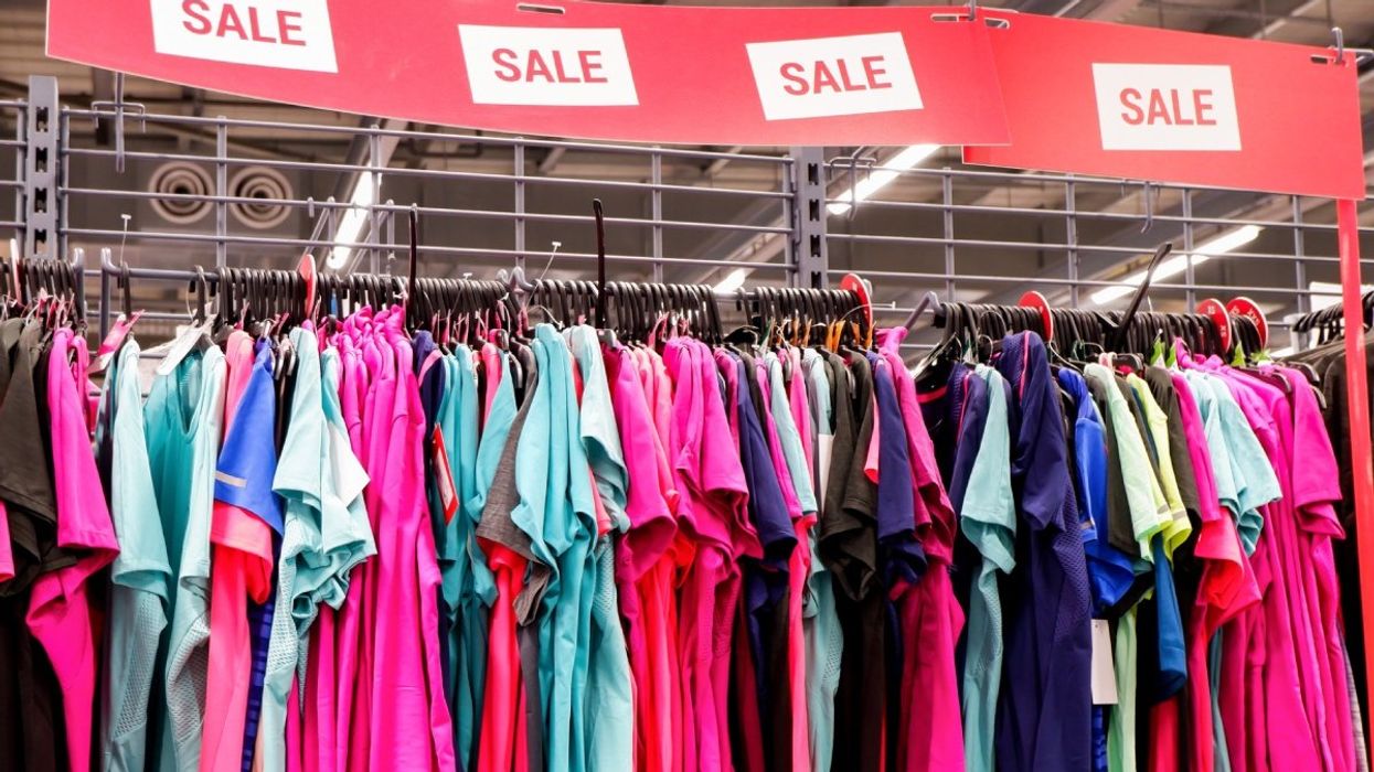 Several colourful t-shirts hung up on a sale rack in a store.