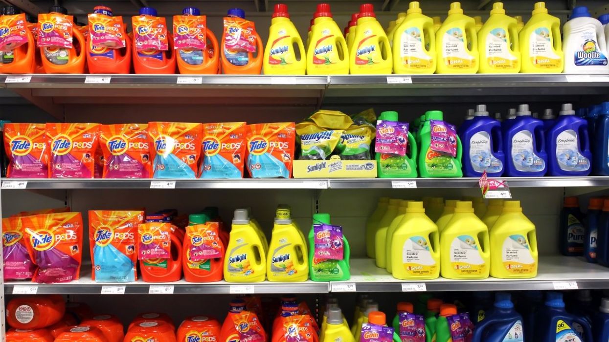 Several different laundry detergent products stacked on shelves at a department store.