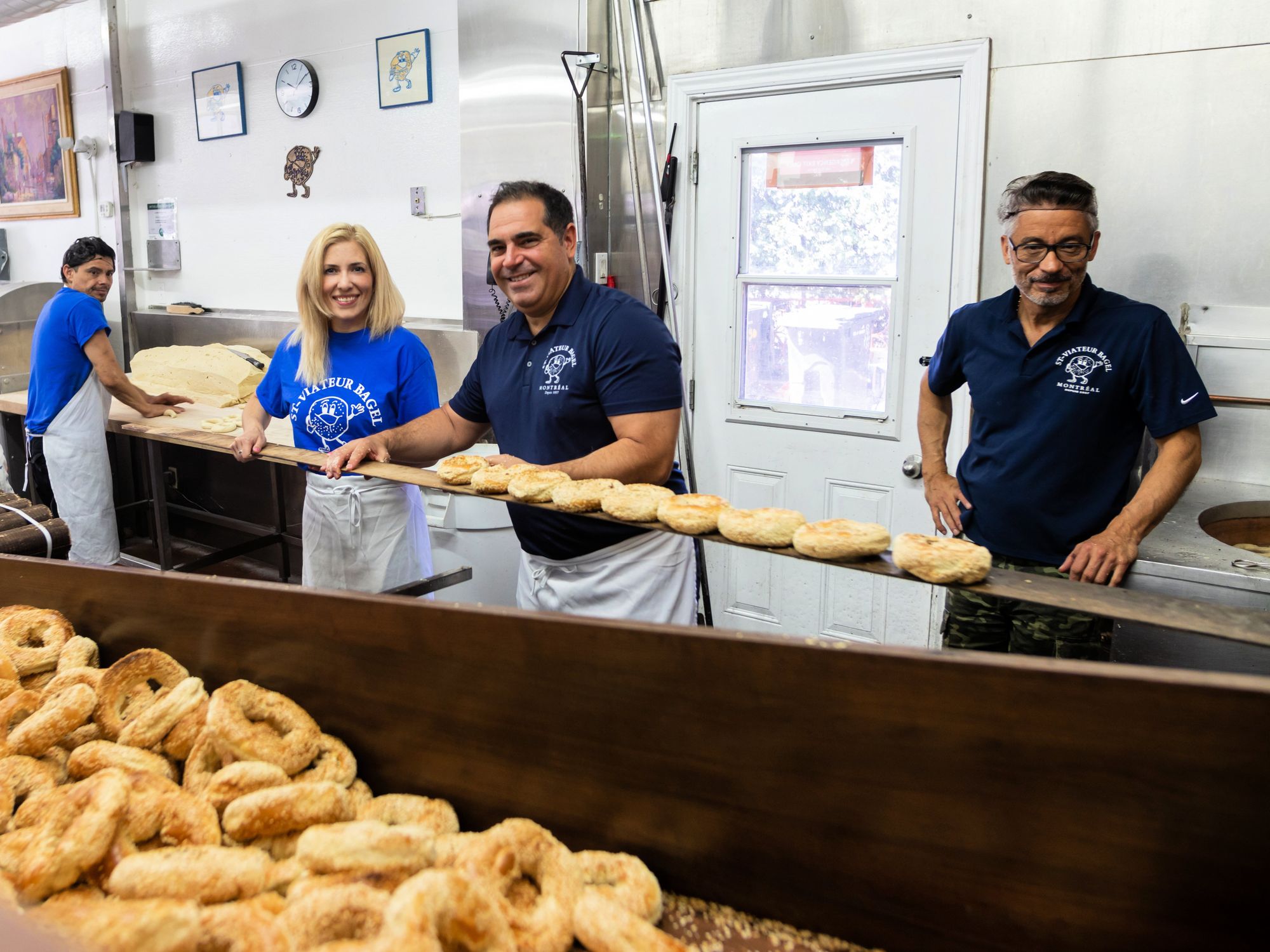 Sofia and Vince take the bagels they prepped out of the oven.