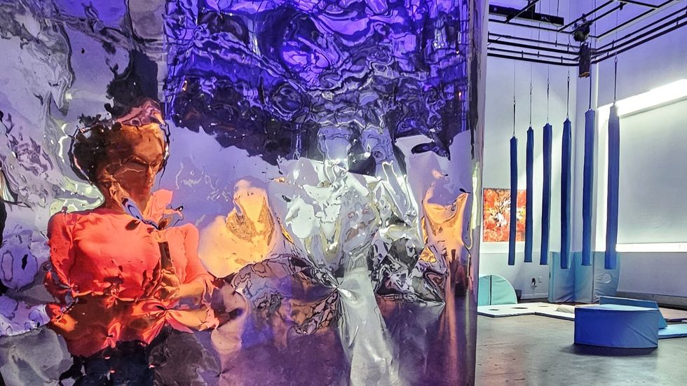 Sofia's distorted reflection in a mirrored surface meant to evoke the sense of falling asleep, with blue objects from "How To Stay Sleepy" visible in the background.