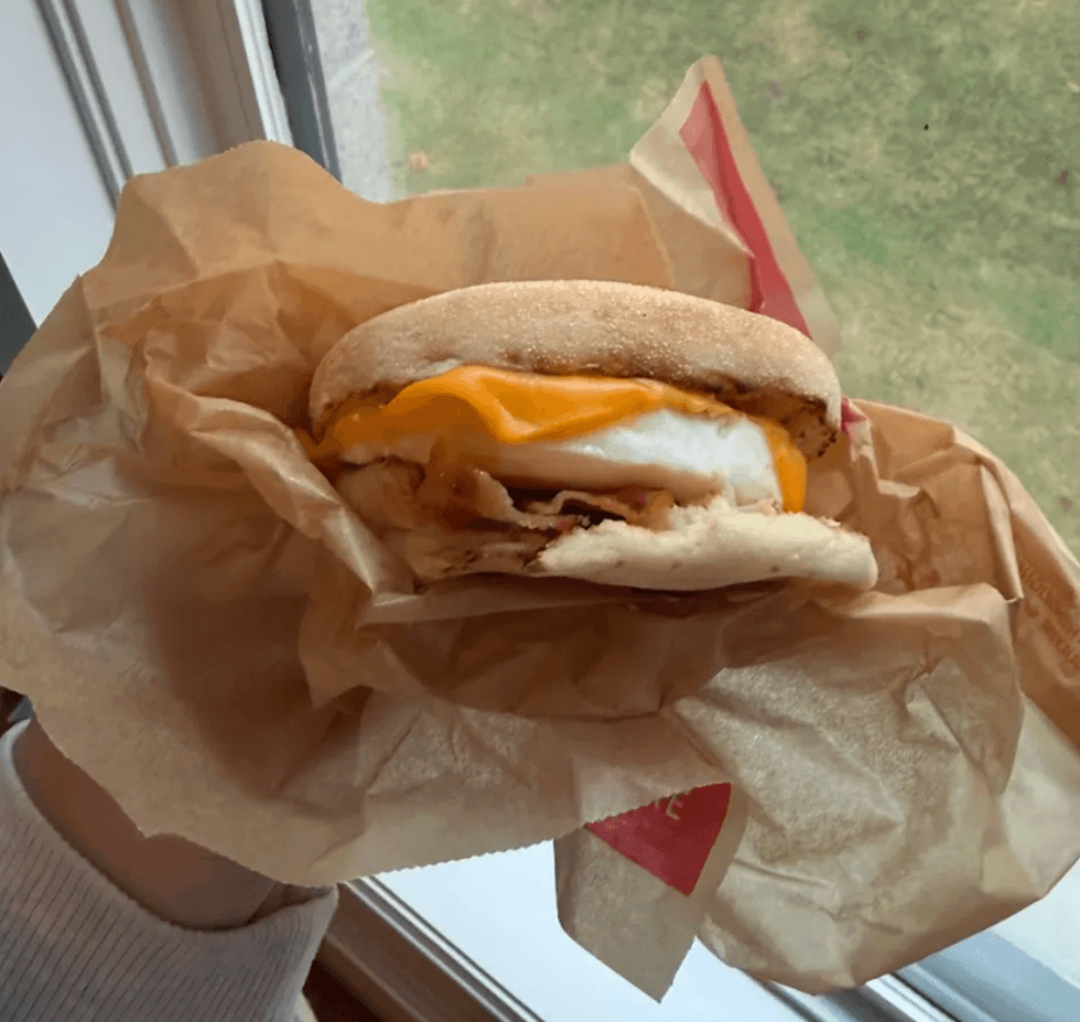 Someone holding a breakfast sandwich.