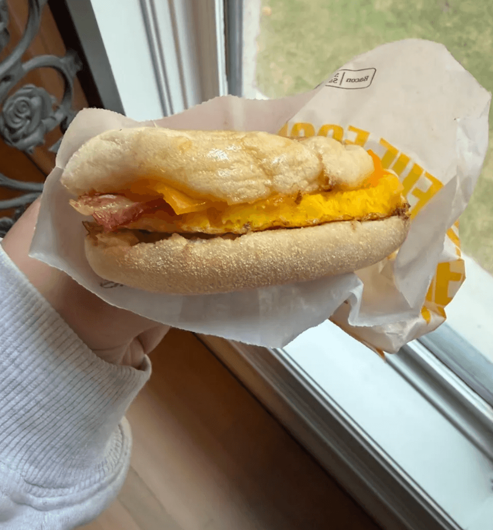 Someone holding a breakfast sandwich.