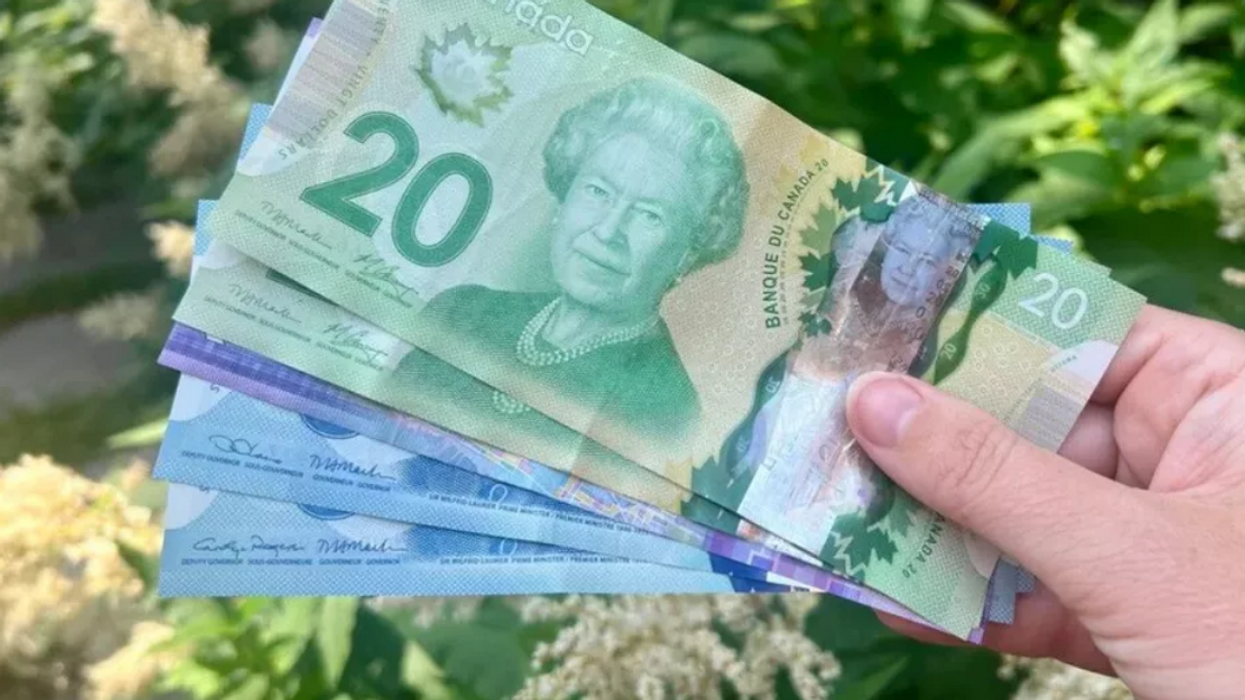 Someone holds a stack of Canadian cash, ranging from $5 bills to $20 bills.