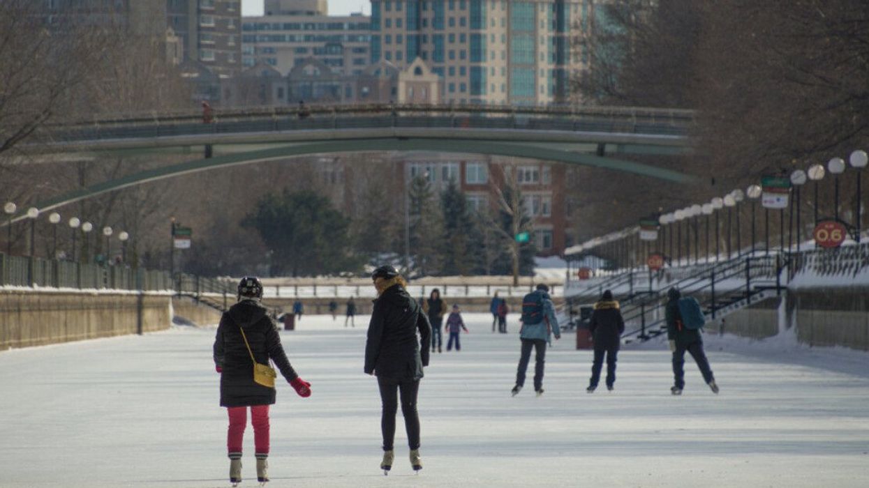 Someone holds out a hand to a fellow ice skater on the frozen-over Rideau Canal in Ottawa.