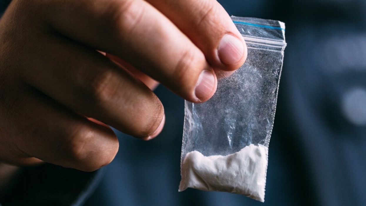 Someone holds up a bag of white powder.