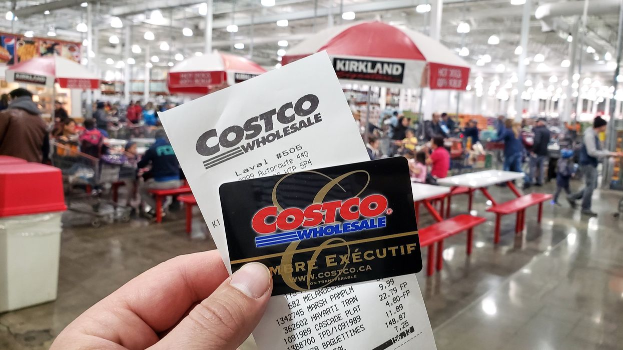 Someone holds up a Costco membership card and receipt inside a Costco in Laval (illustrative).