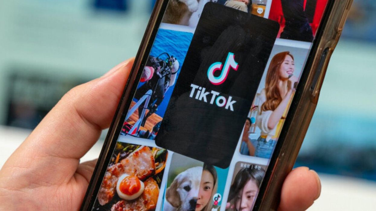 Someone holds up a smartphone with TikTok open on the screen.