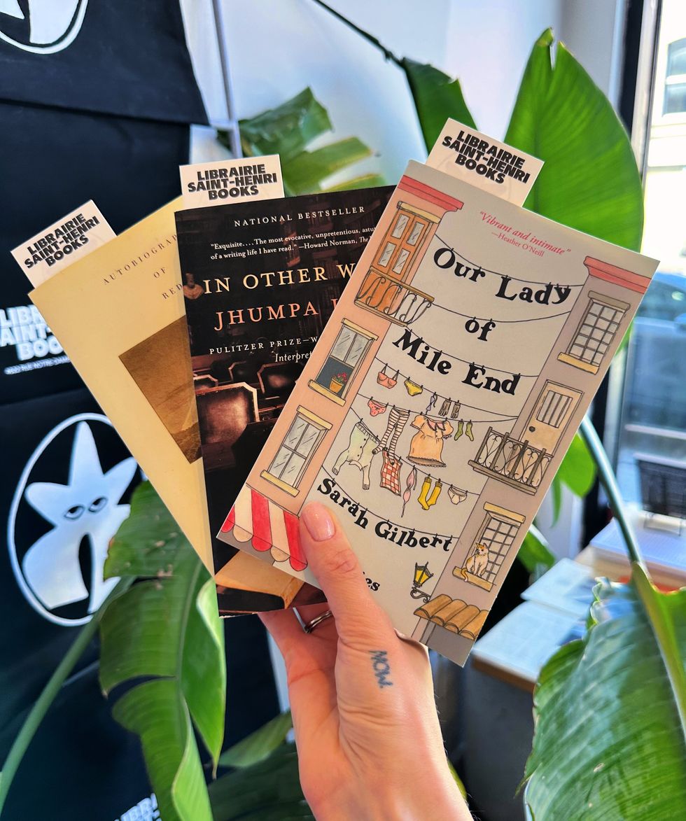 Someone holds up books "Our Lady of Mile End," "In Other Words" and "The Autobiography of Red."