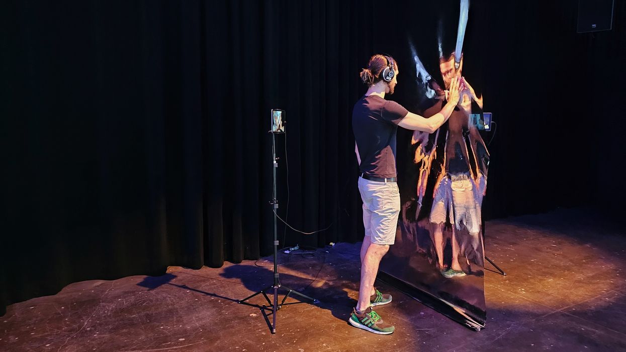 Someone interacts with a transluscent material that distorts their reflection, as if in a dream.