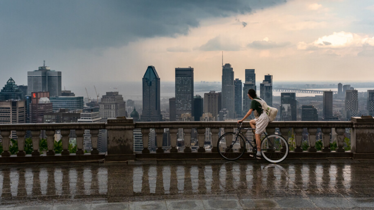 Someone on a bicycle looks out at the Montreal skyline as a storm approaches.