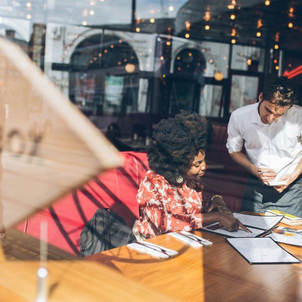 Someone orders something off of a menu while a server looks on.