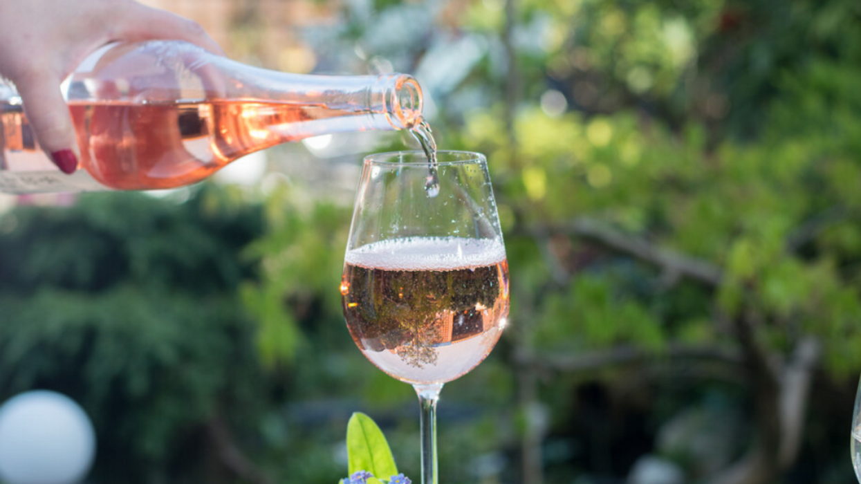 Someone pours rosé into a wine glass.