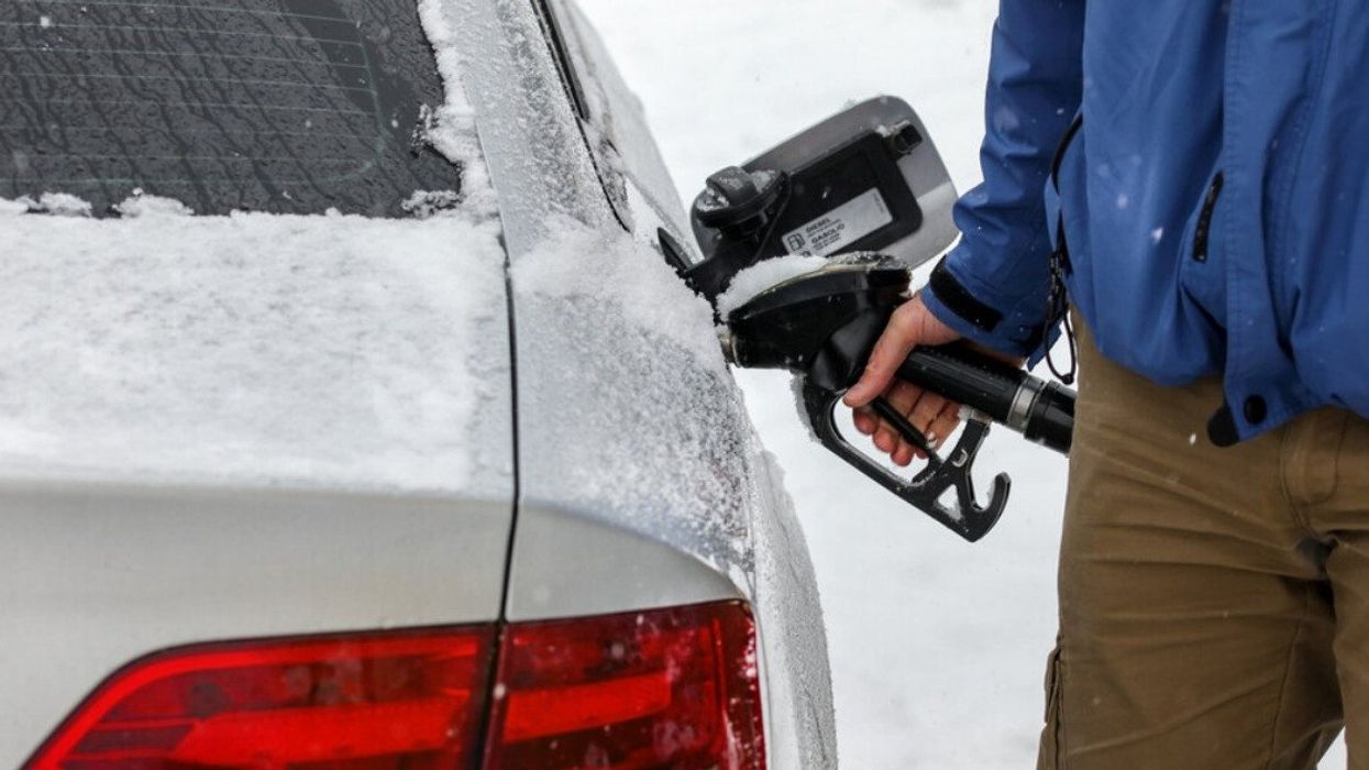 Someone pumps gas in the snow.