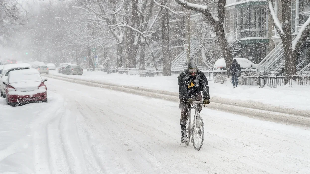 Someone rides a bicycle through the streets of Montreal, Quebec, Canada during a snowstorm.