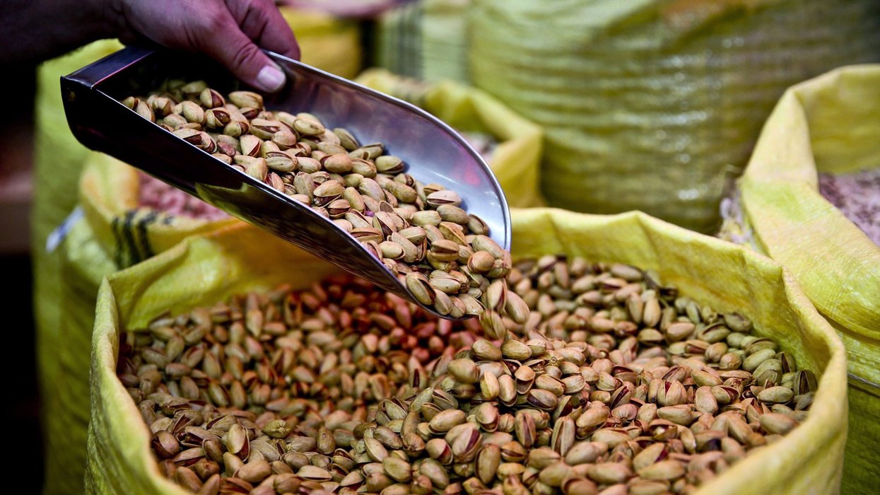 Someone scoops bulk pistachios from a bag.